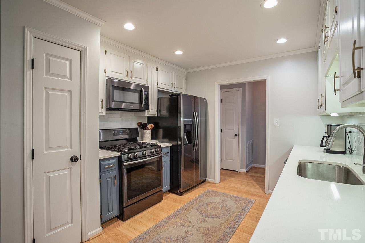 8105 Brumbley Place Raleigh, NC 27612 - Photo 10 of 23 a kitchen with kitchen island stainless steel appliances a stove a sink and a refrigerator