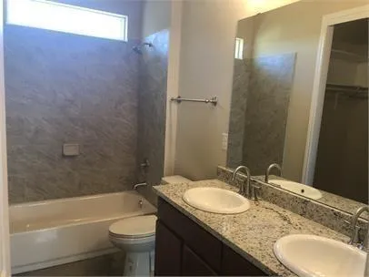 a bathroom with a granite countertop sink a toilet and shower