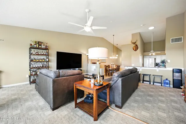 a living room with furniture kitchen view and a chandelier