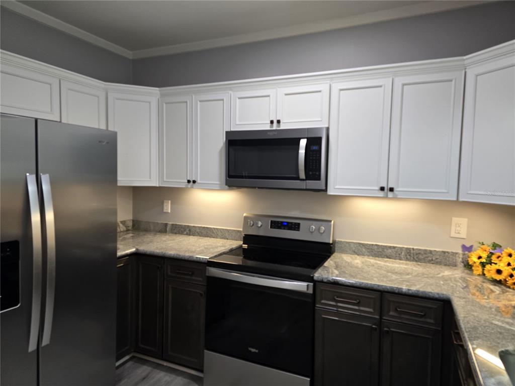 326 Southeast 2nd Street Williston, FL 32696 - Photo 9 of 30 a kitchen with stainless steel appliances granite countertop a refrigerator stove top oven and sink with cabinets
