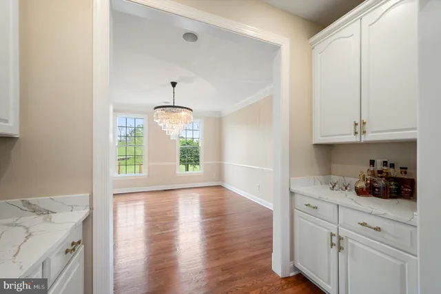 a hallway with white cabinets and wooden floor