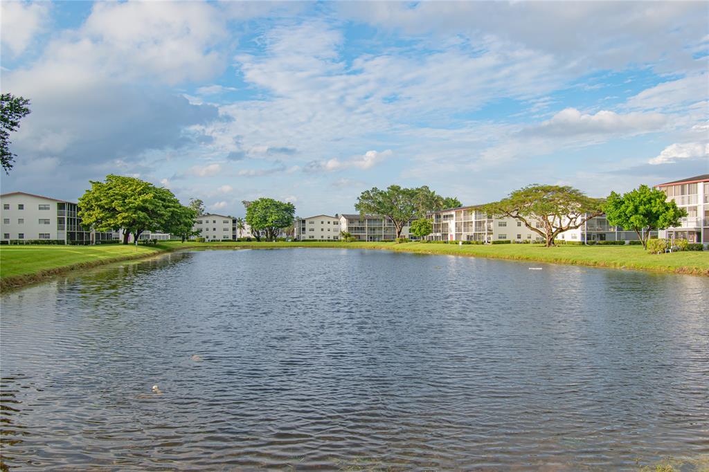 436 Fanshaw K, Unit 436 Boca Raton, FL 33434 - Photo 2 of 16 a view of a lake with a big yard and large trees