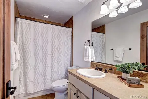 a bathroom with a granite countertop sink a toilet and a mirror