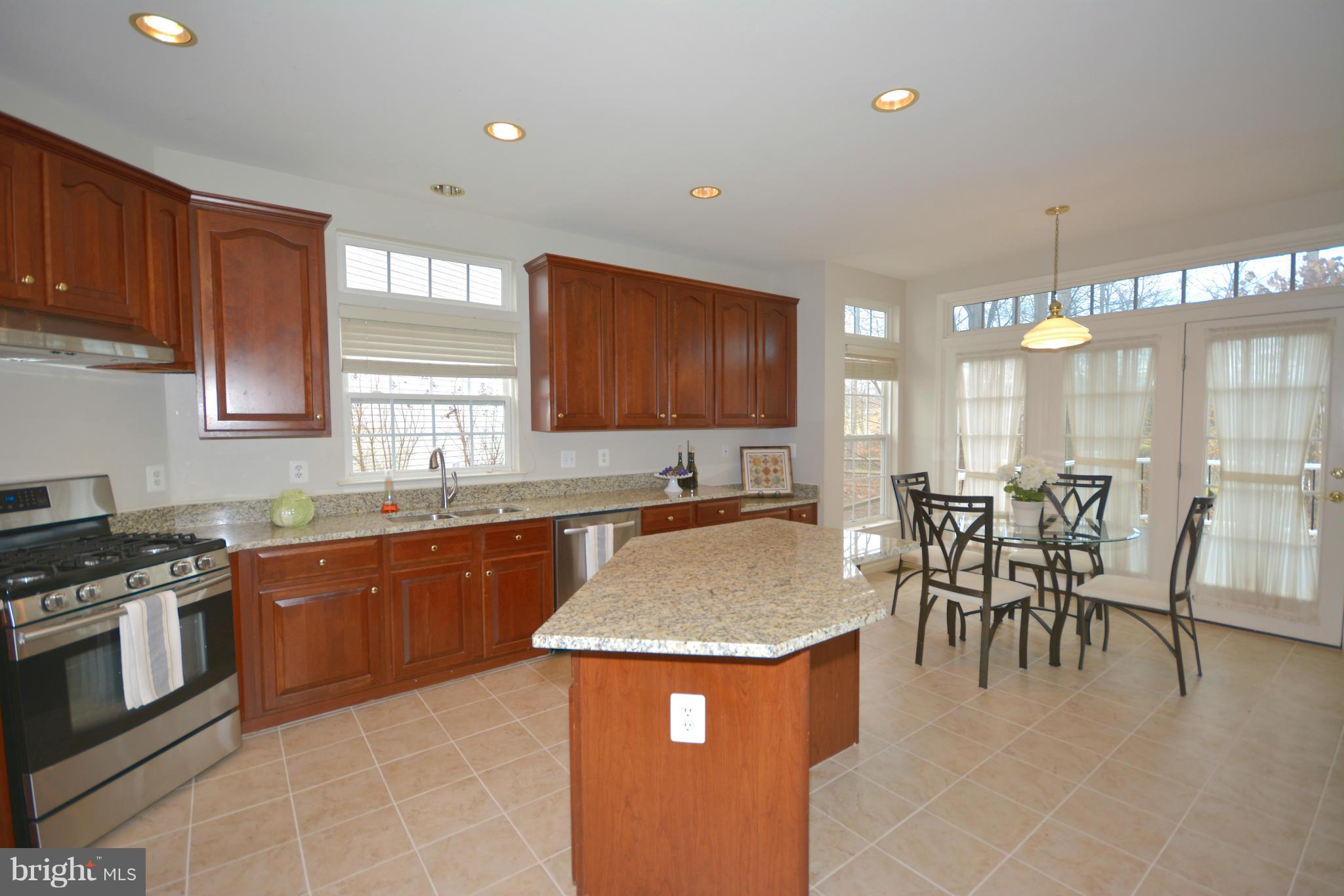 14468 Clubhouse Road Gainesville, VA 20155 - Photo 10 of 30 a kitchen with granite countertop a stove a sink a dining table and chairs