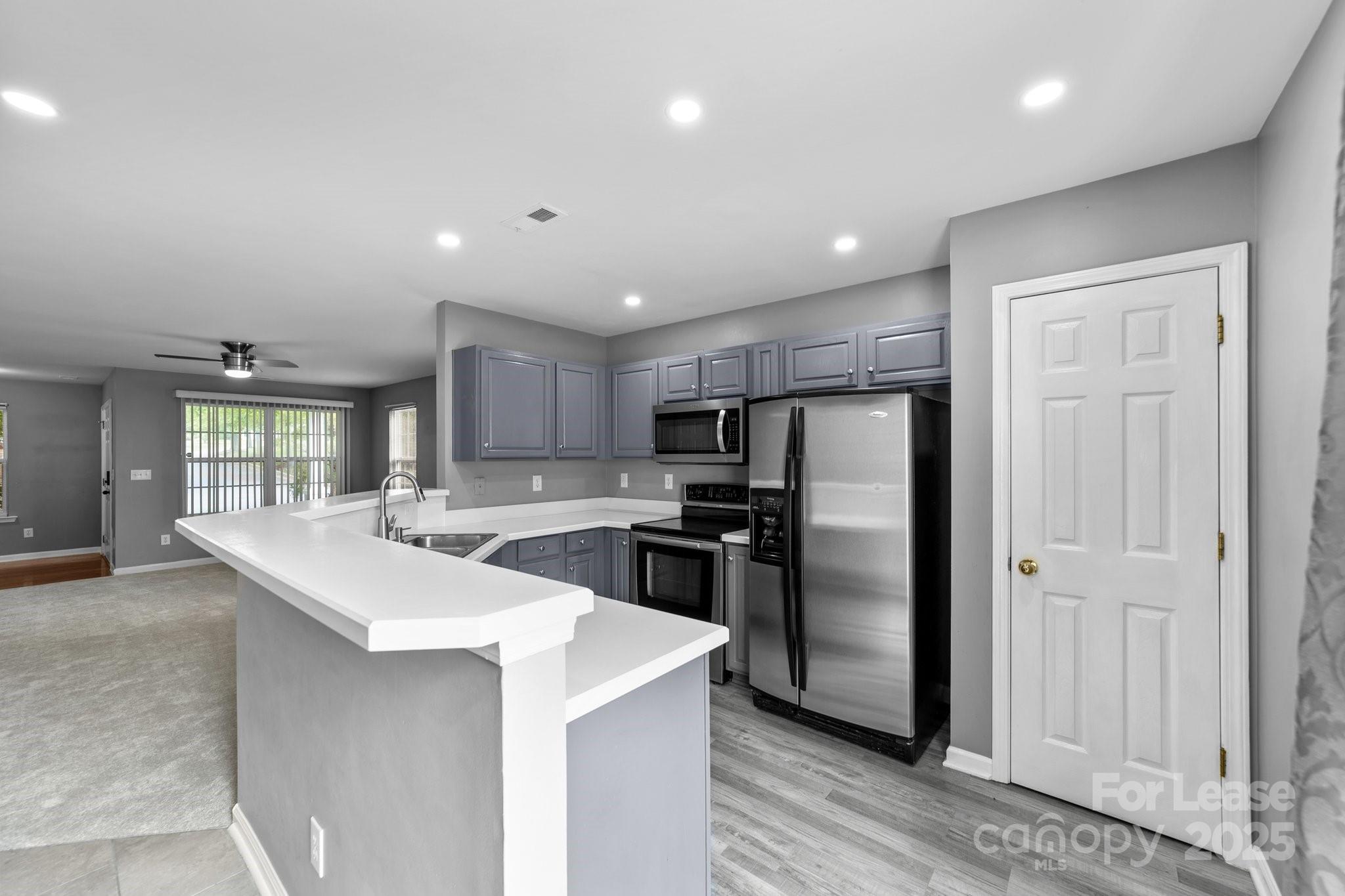 a kitchen with stainless steel appliances granite countertop a refrigerator a sink a stove and oven