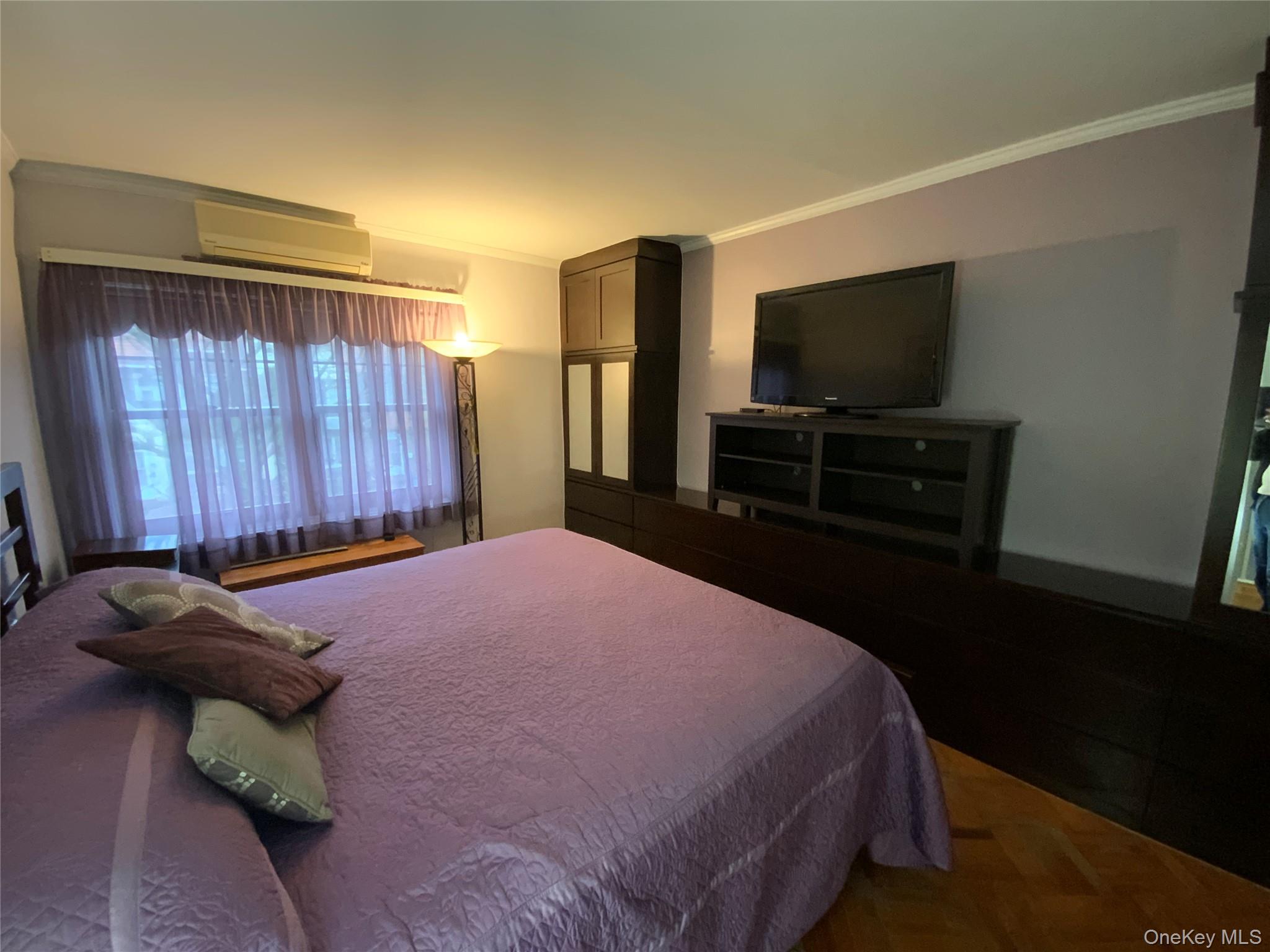 47-05 189th Street Queens, NY 11358 - Photo 26 of 41 a bedroom with a bed and a flat tv screen on dresser