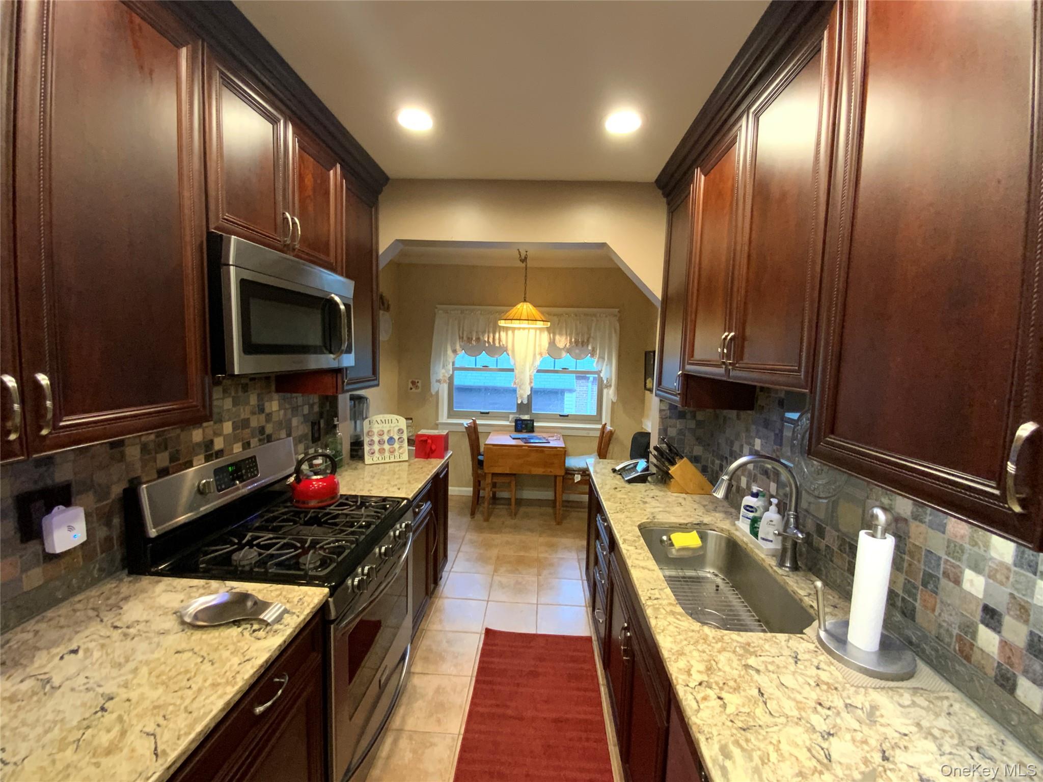 47-05 189th Street Queens, NY 11358 - Photo 10 of 41 a kitchen with granite countertop lots of counter top space a sink stainless steel appliances and cabinets