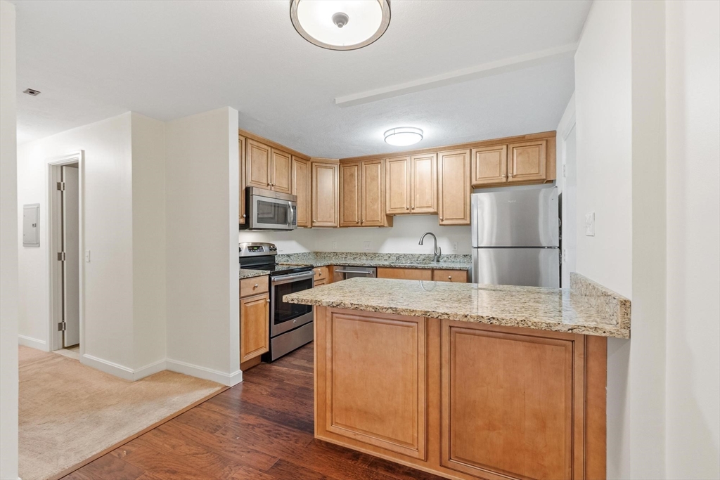 420 Great Road, Unit C1 Acton, MA 01720 - Photo 5 of 29 a kitchen with granite countertop a refrigerator stove top oven and sink