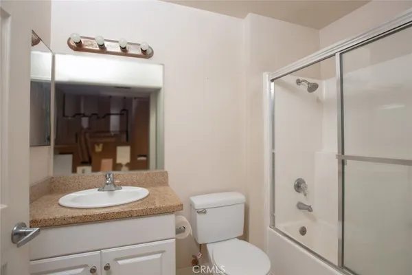 a bathroom with a granite countertop sink toilet a mirror and shower