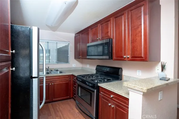 a kitchen with stainless steel appliances granite countertop a stove a sink dishwasher and a microwave oven with cabinets