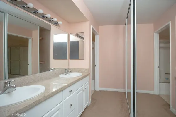 a bathroom with a granite countertop double vanity and a mirror