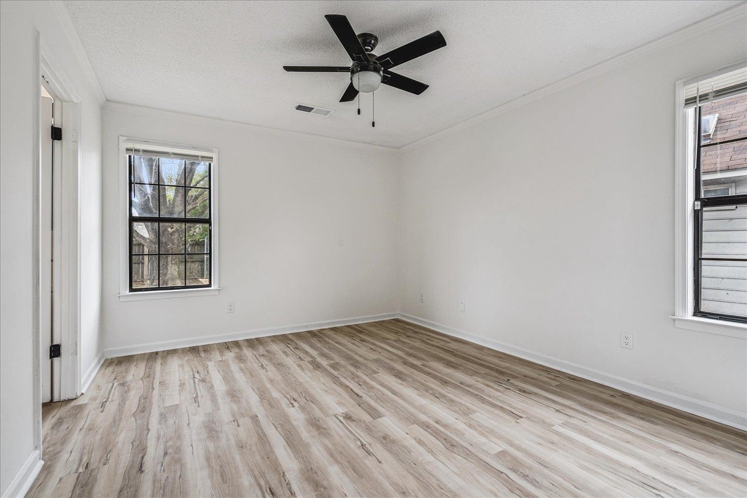 5287 Shady Ridge Drive Memphis, TN 38141 - Photo 11 of 13 Empty room featuring light wood-type flooring, ornamental molding, a ceiling fan, a textured ceiling, and healthy amount of natural light