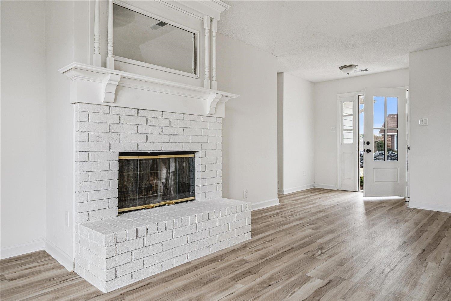 5287 Shady Ridge Drive Memphis, TN 38141 - Photo 3 of 13 Unfurnished living room with a brick fireplace, light wood-style flooring, and a textured ceiling