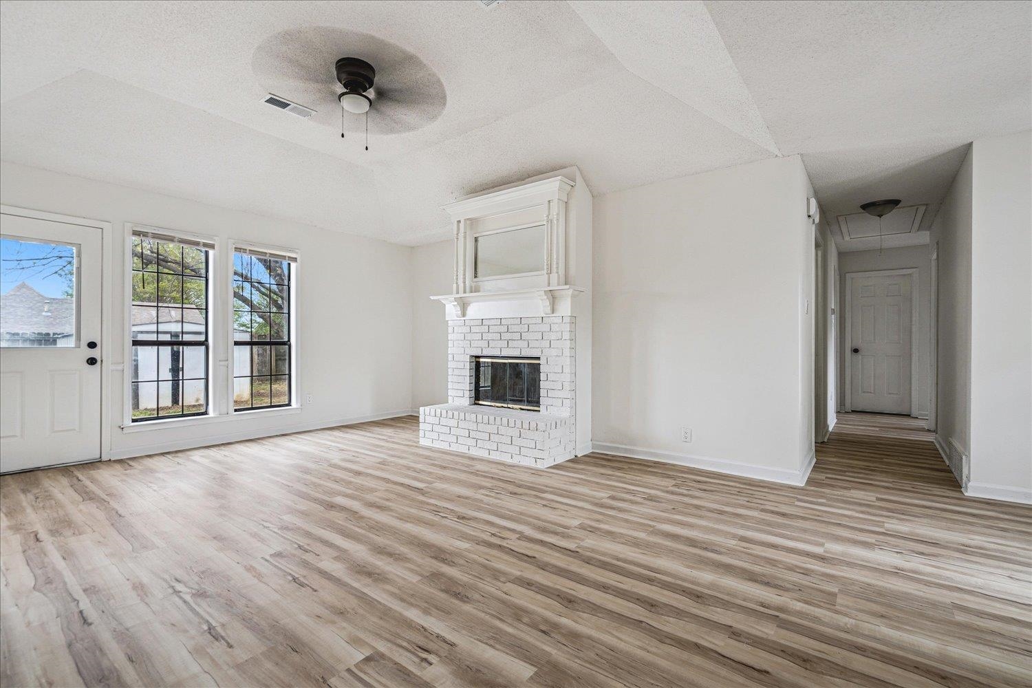 5287 Shady Ridge Drive Memphis, TN 38141 - Photo 4 of 13 Unfurnished living room featuring light wood-type flooring, ceiling fan, and a brick fireplace
