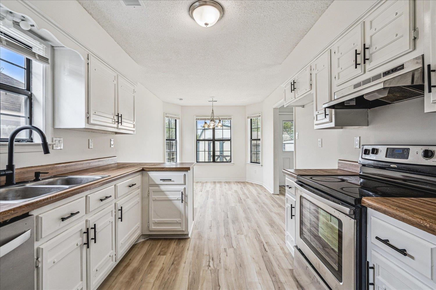 5287 Shady Ridge Drive Memphis, TN 38141 - Photo 6 of 13 Kitchen with stainless steel appliances, light wood-type flooring, a textured ceiling, suspended lighting, and white cabinets