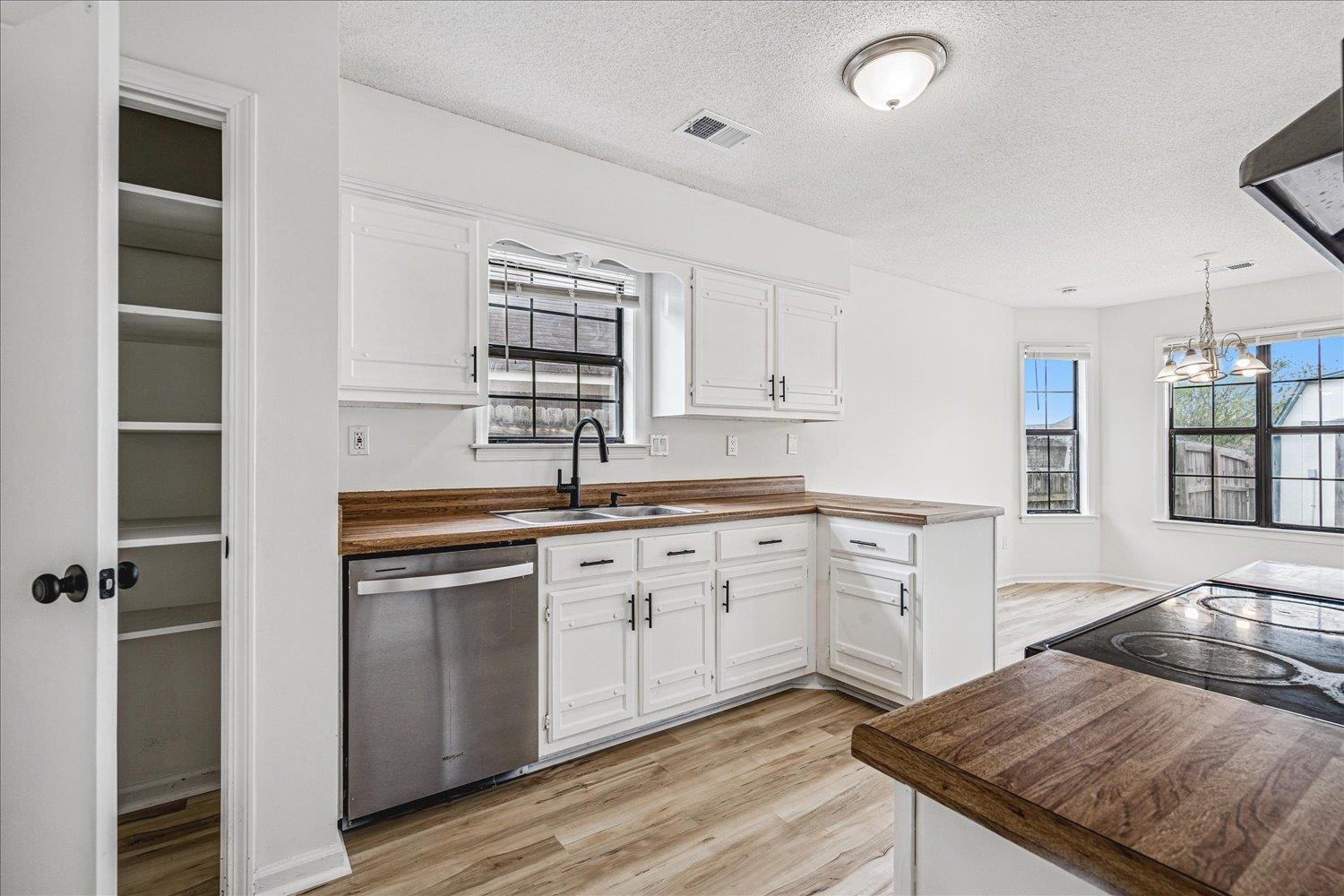 5287 Shady Ridge Drive Memphis, TN 38141 - Photo 7 of 13 Kitchen with light wood finished floors, stainless steel dishwasher, white cabinetry, and a textured ceiling