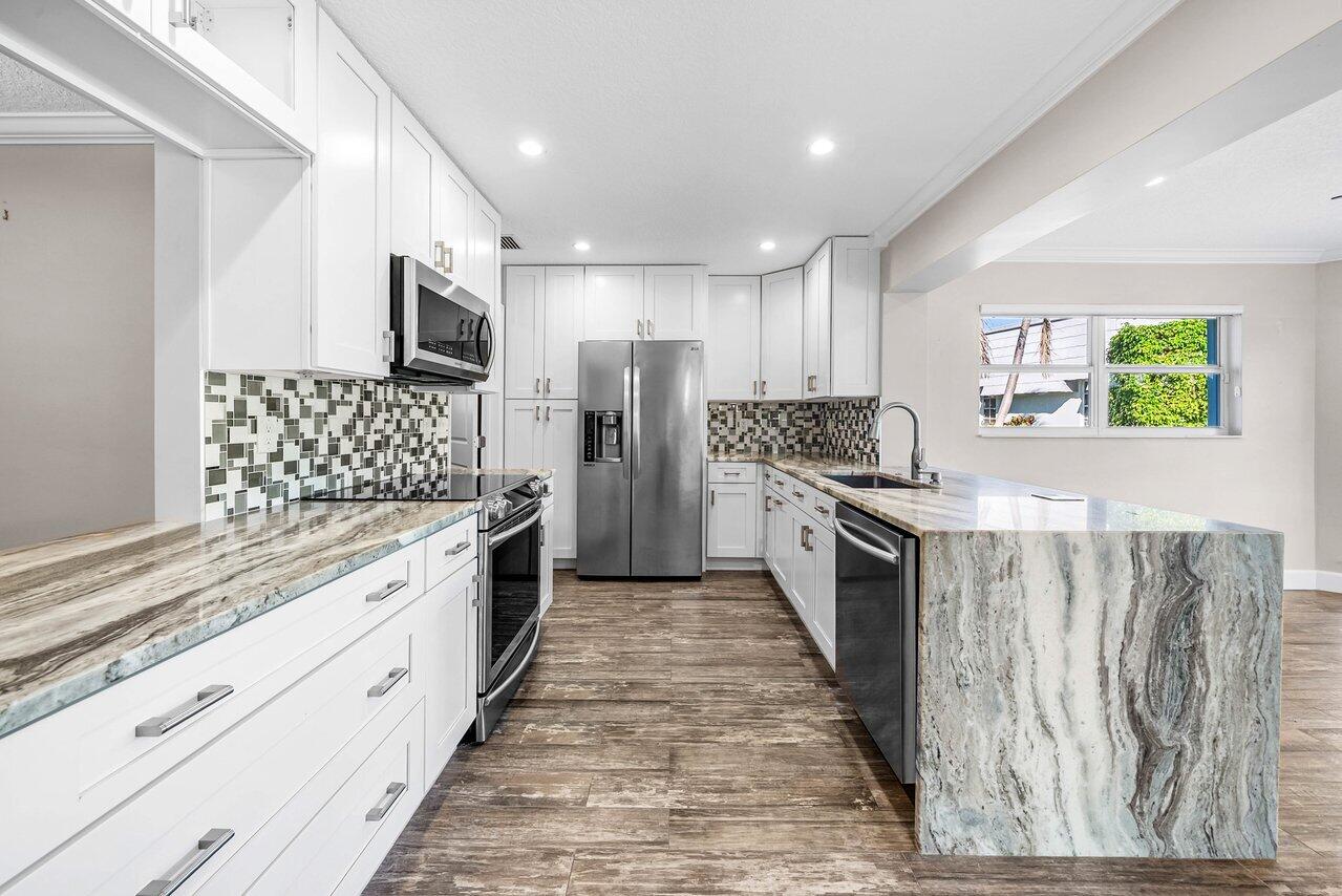 401 French Royale Circle Atlantis, FL 33462 - Photo 12 of 47 a large kitchen with stainless steel appliances kitchen island granite countertop a stove a sink and a refrigerator