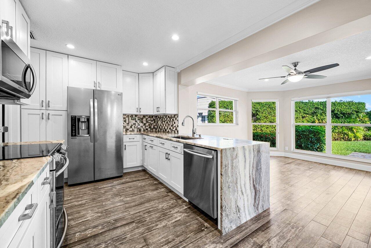 401 French Royale Circle Atlantis, FL 33462 - Photo 14 of 47 a kitchen with granite countertop a refrigerator and a sink