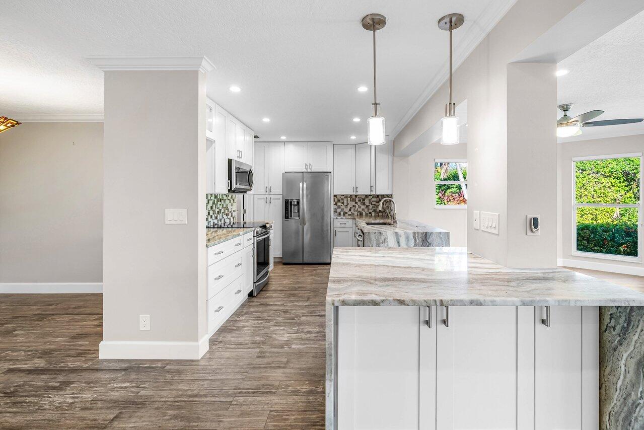 401 French Royale Circle Atlantis, FL 33462 - Photo 15 of 47 a kitchen with kitchen island granite countertop a large counter top stainless steel appliances and cabinets