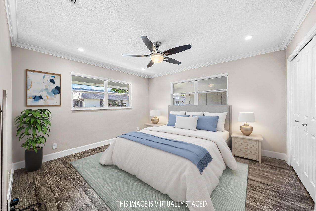 401 French Royale Circle Atlantis, FL 33462 - Photo 30 of 47 a bedroom with a large bed chandelier and a window