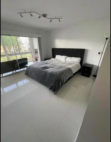 a spacious bedroom with a bed a large window with outer view and couch