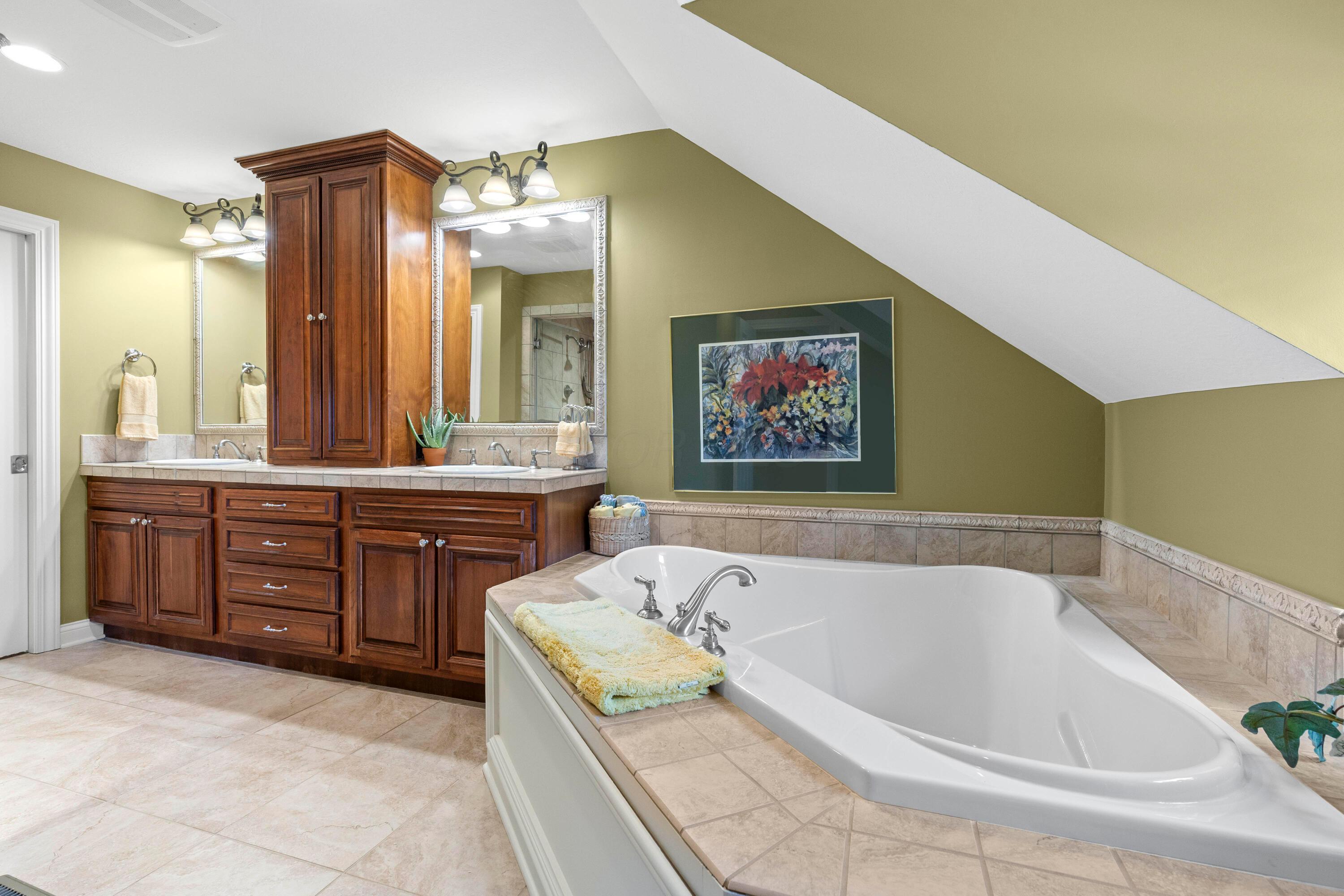5701 Lancaster-Circleville Road Southwest Lancaster, OH 43130 - Photo 50 of 144 • Ceramic tile flooring • Sage painted walls • Garden tub with ceramic tile surround • (2) 3 bulb wall lights • Linen towel holder/medicine cabinet • Enclosed vanity with double bowl, ceramic tile sinktop • Steam shower with full ceramic tile surround & glass doors • New steam shower controller ~ 2023 • Heated towel rack is negotiable