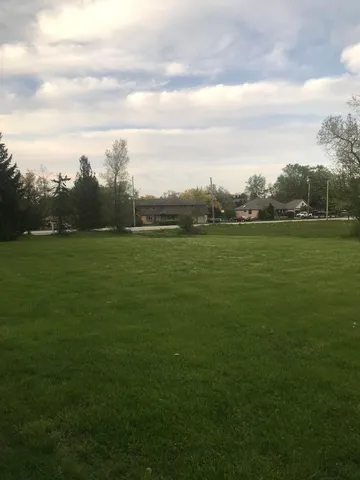 an aerial view of a residential houses with outdoor space and trees all around