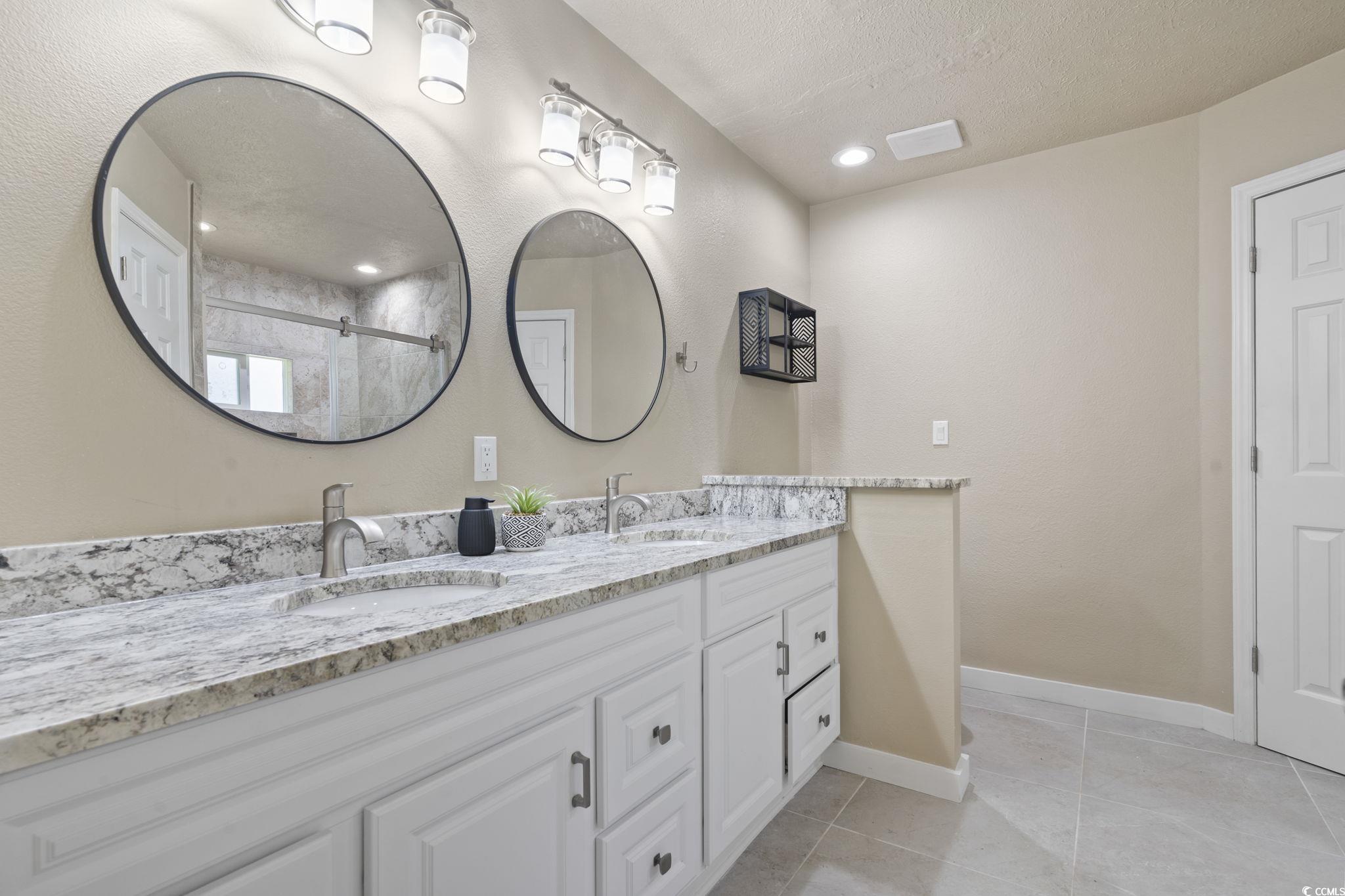 220 Rice Mill Drive Myrtle Beach, SC 29588 - Photo 16 of 31 Bathroom featuring double vanity, a textured ceiling, recessed lighting, a tile shower, and tile patterned flooring