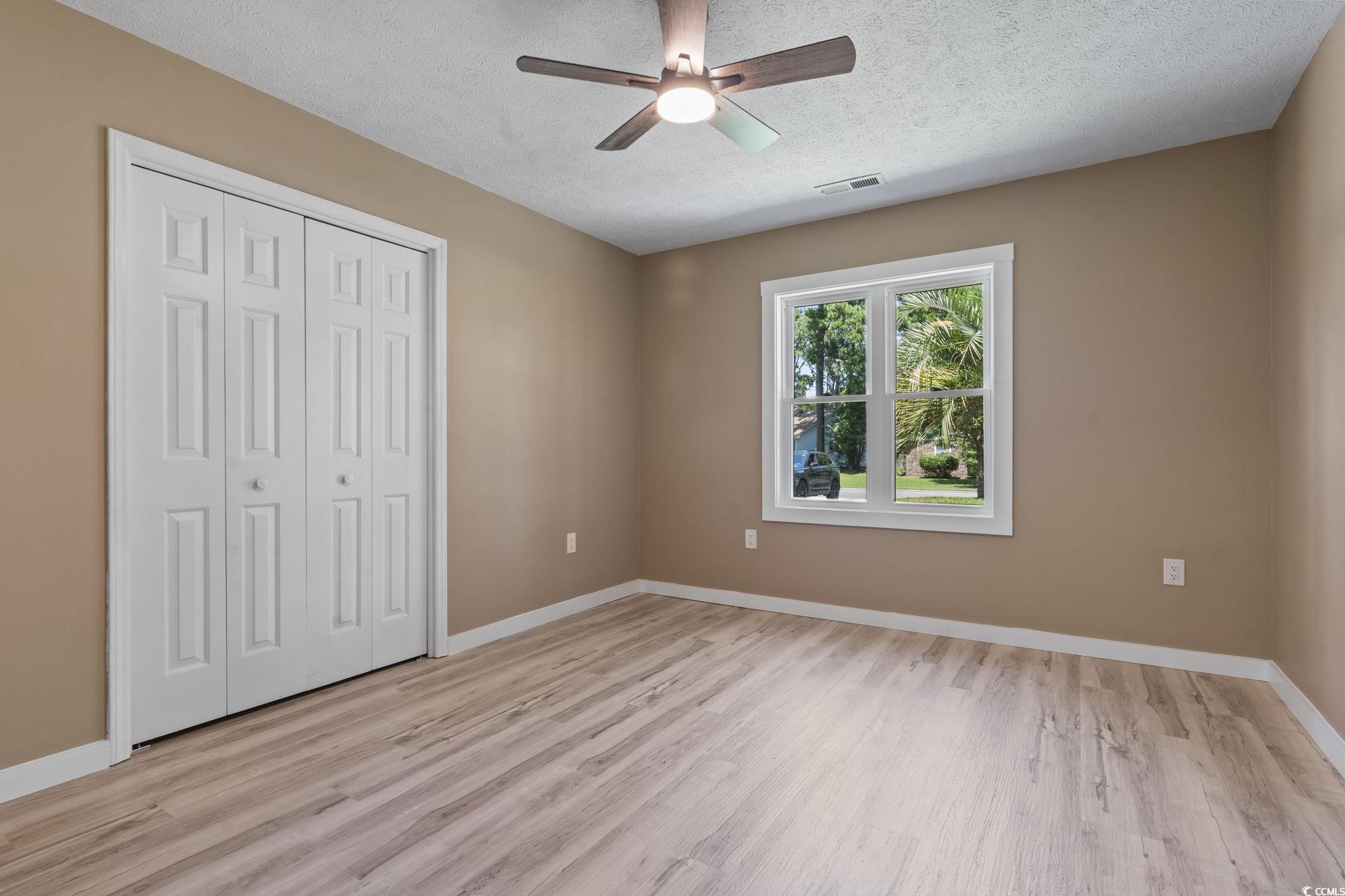 220 Rice Mill Drive Myrtle Beach, SC 29588 - Photo 19 of 31 Unfurnished bedroom with a closet, light wood-style floors, a textured ceiling, and a ceiling fan