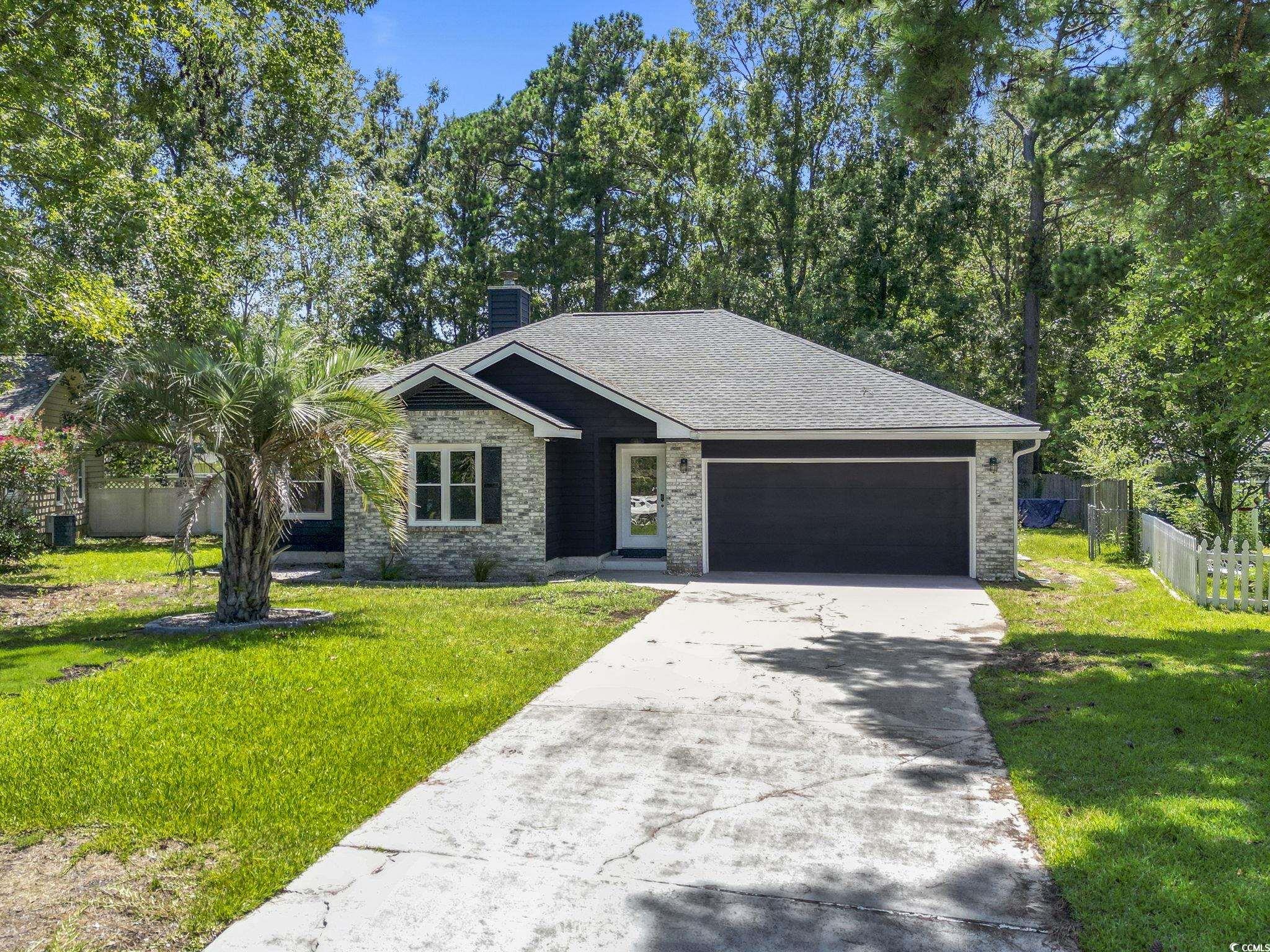 220 Rice Mill Drive Myrtle Beach, SC 29588 - Photo 3 of 31 View of front of home featuring a chimney, concrete driveway, roof with shingles, an attached garage, and brick siding