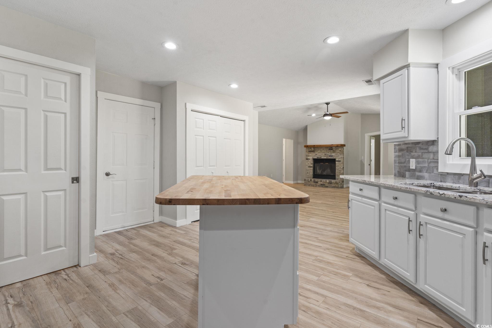 220 Rice Mill Drive Myrtle Beach, SC 29588 - Photo 5 of 31 Kitchen featuring a ceiling fan, wood counters, tasteful backsplash, a center island, and a fireplace