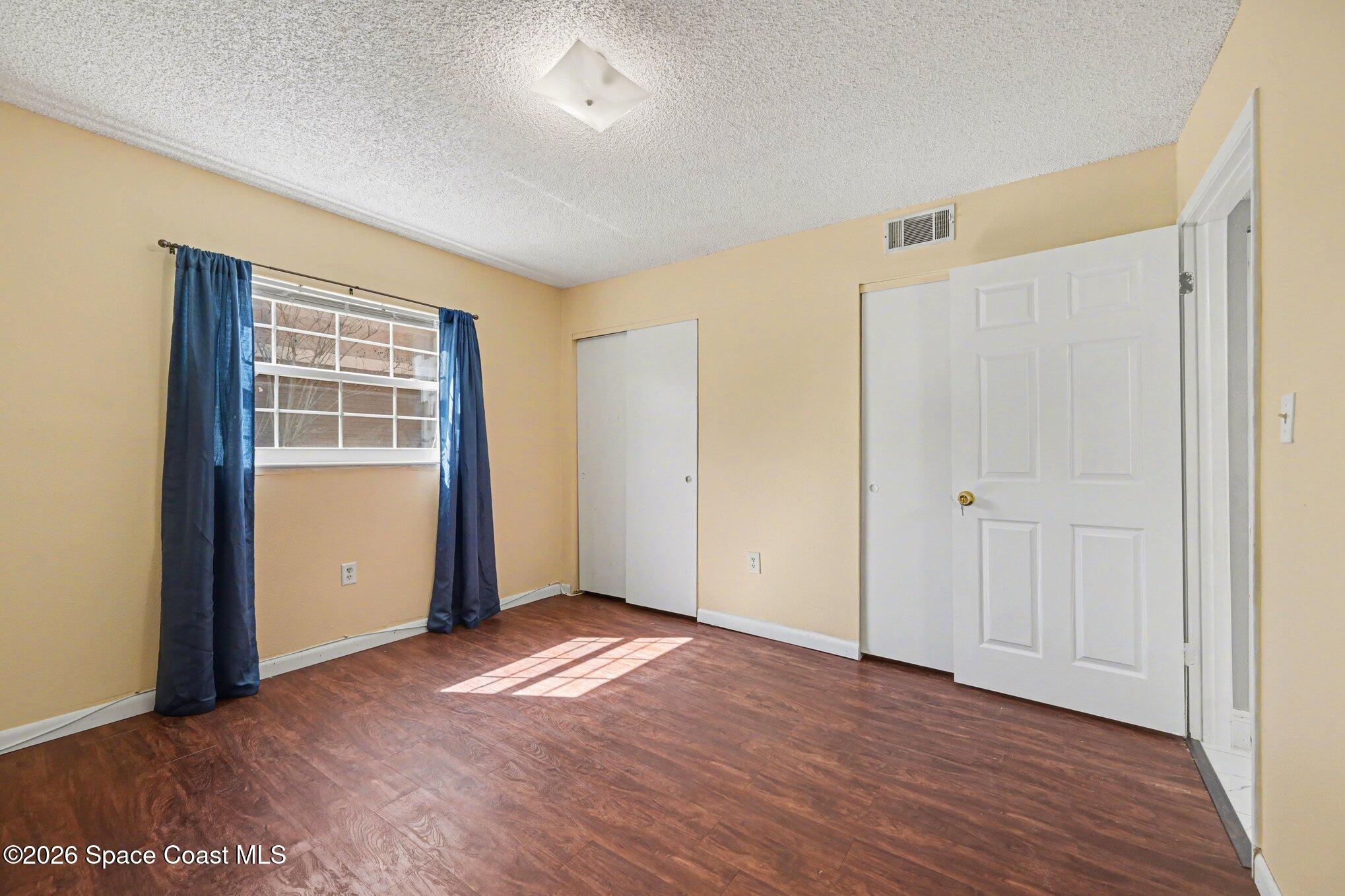101 Bristol Lane, Unit 101 Melbourne, FL 32935 - Photo 12 of 16 an empty room with wooden floor and windows