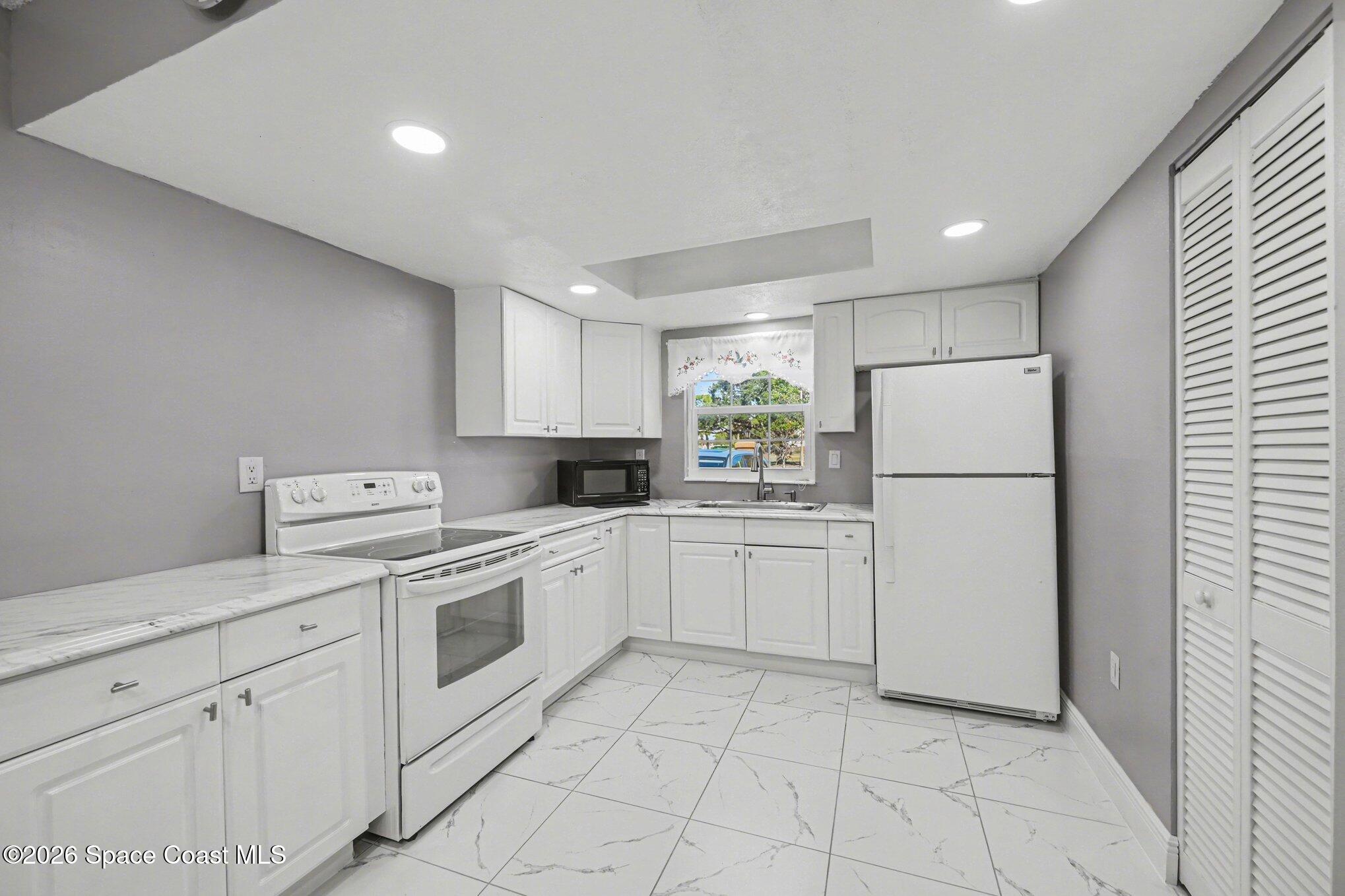 101 Bristol Lane, Unit 101 Melbourne, FL 32935 - Photo 4 of 16 a kitchen with white cabinets and white appliances