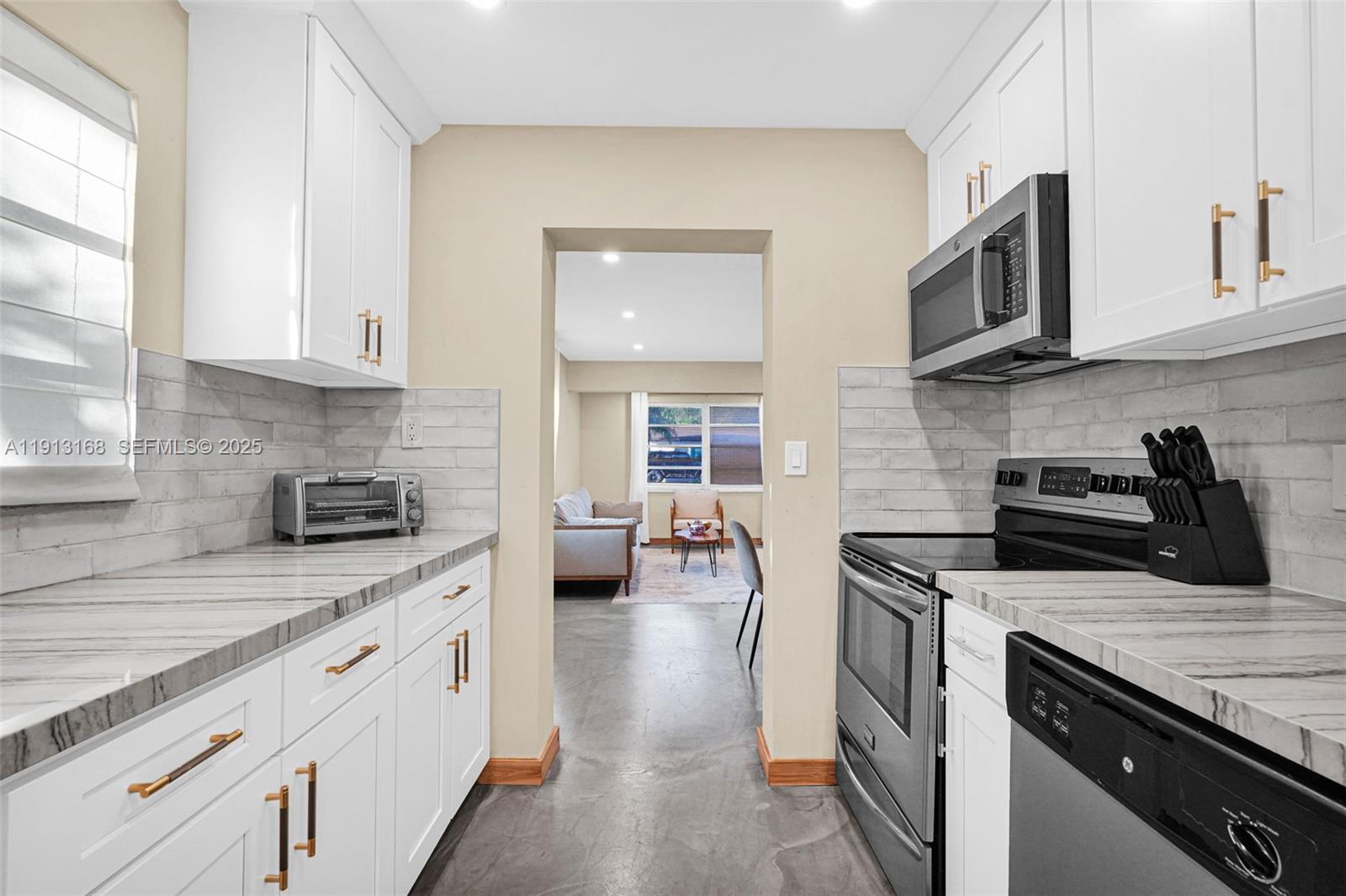 1012 Northeast 2nd Street Hallandale Beach, FL 33009 - Photo 44 of 65 a kitchen with stainless steel appliances granite countertop a sink stove and cabinets