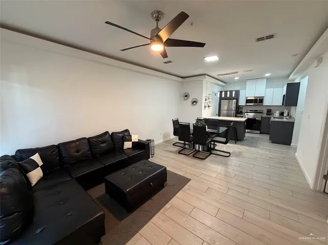 a living room with furniture and a dining table with wooden floor
