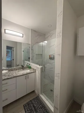 a bathroom with a granite countertop sink a mirror and a shower