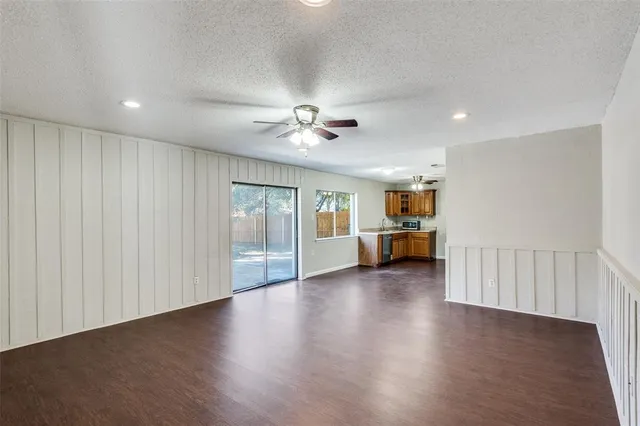 a view of an empty room with wooden floor and a ceiling fan