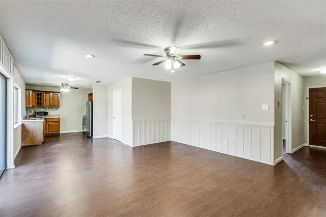 a view of an empty room with a kitchen and a window
