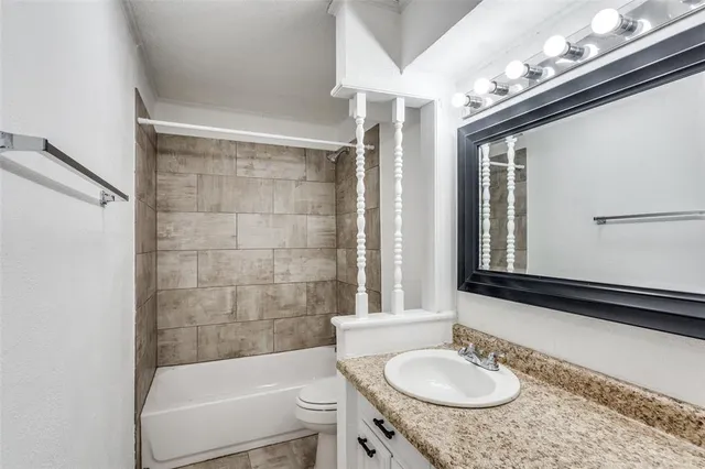 a bathroom with a granite countertop sink mirror toilet and bathtub