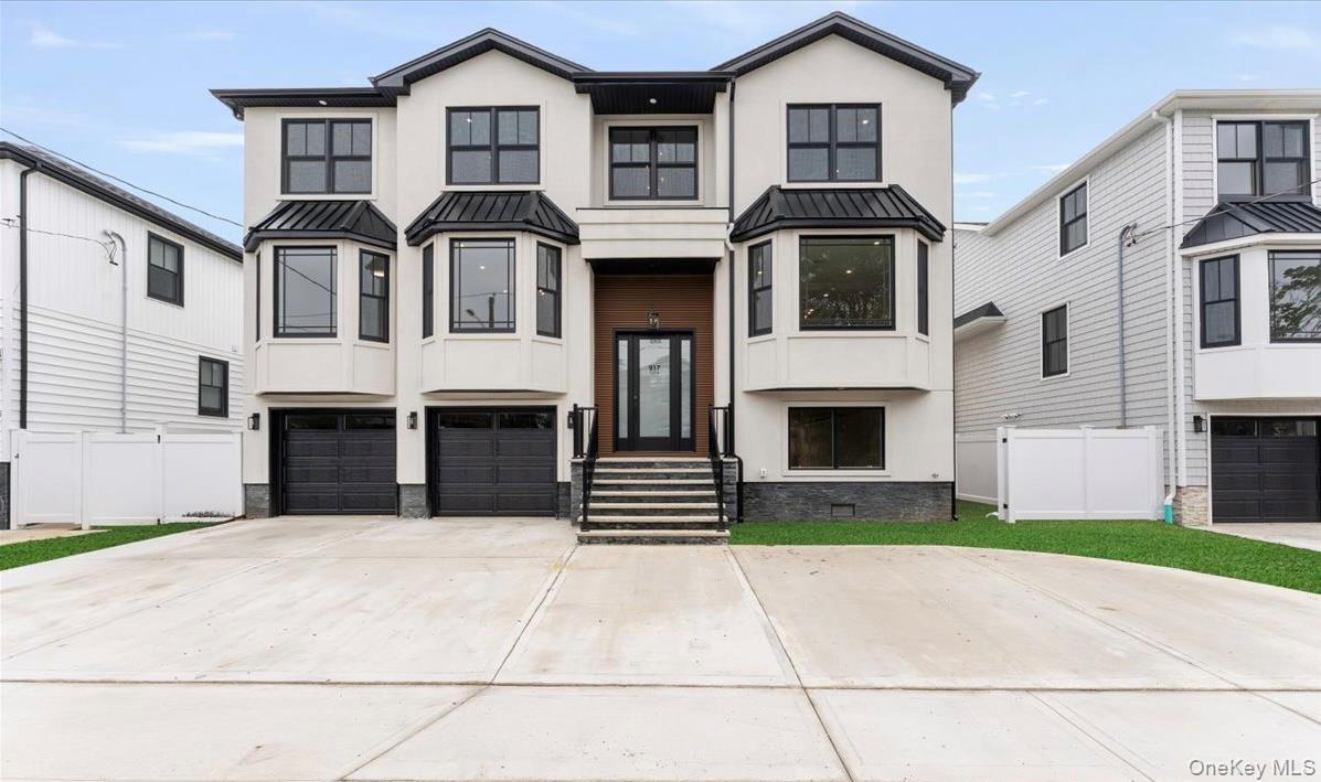 View of front facade with a standing seam roof, a metal roof, stucco siding, and driveway