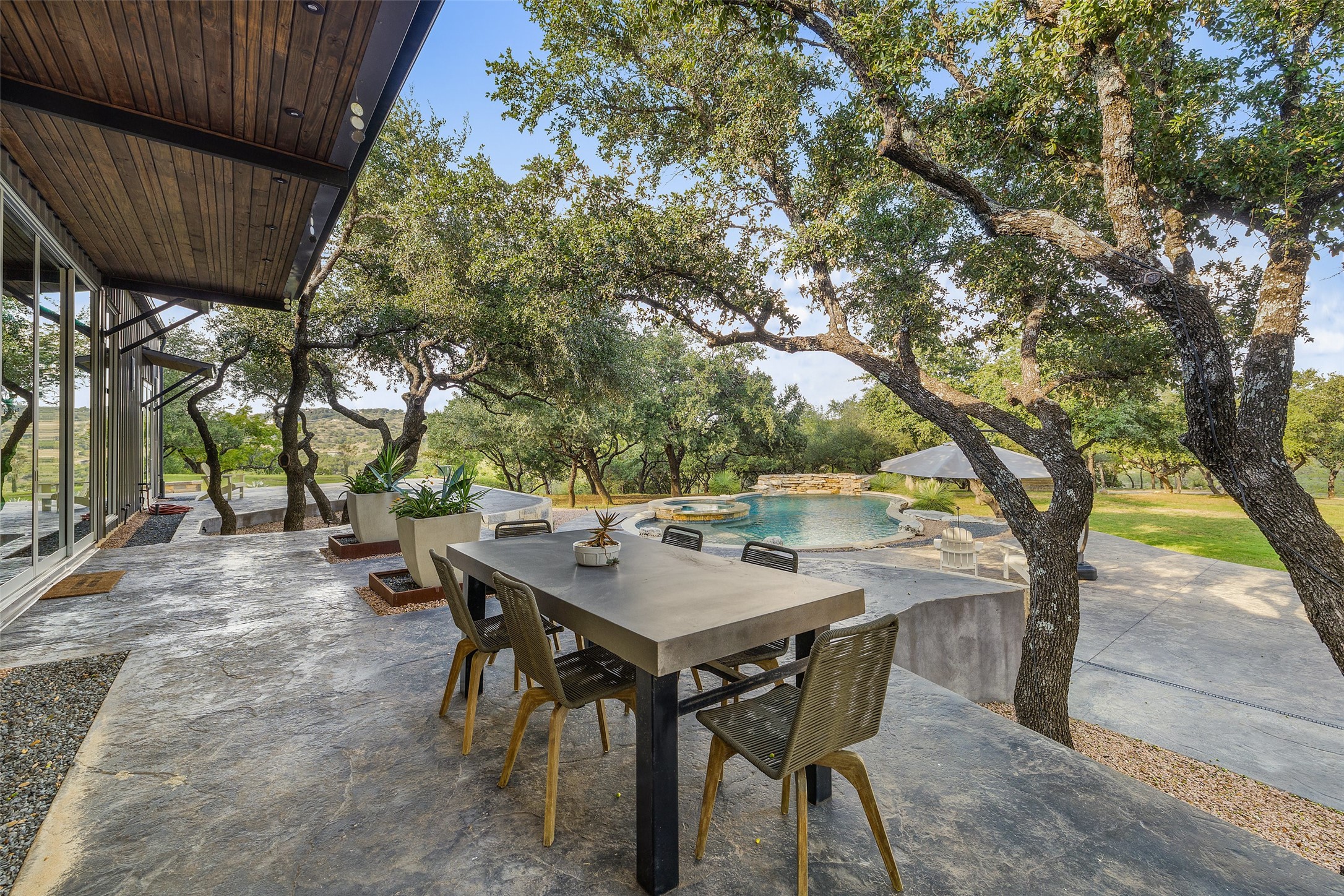 2412 Bee Creek Road Spicewood, TX 78669 - Photo 21 of 40 a view of backyard with table and chairs and a large tree