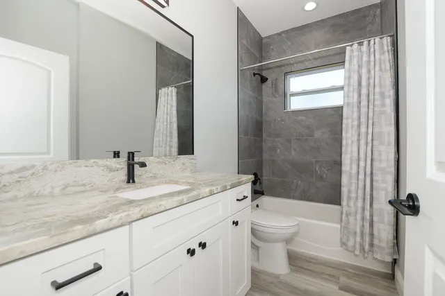 a bathroom with a granite countertop sink a toilet and shower