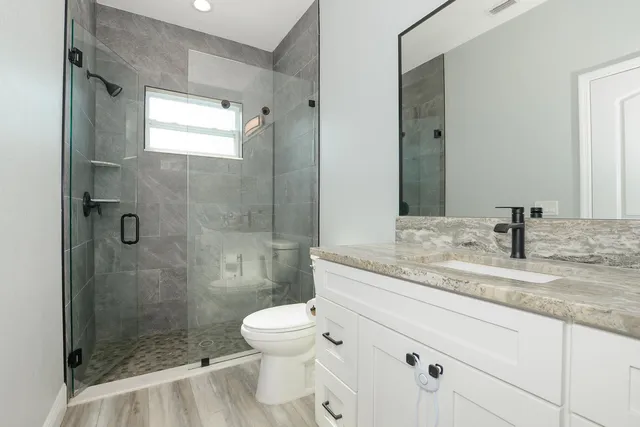 a bathroom with a granite countertop sink toilet and shower