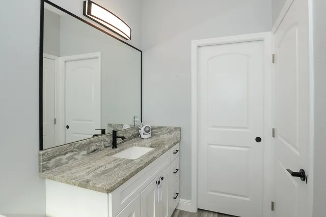 a bathroom with a granite countertop sink and a mirror