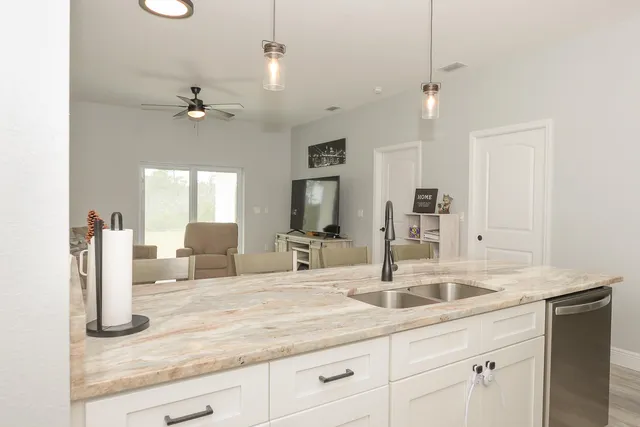 a kitchen with kitchen island a sink granite counter tops and a view of living room