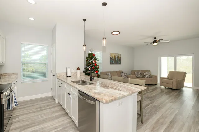 a kitchen with granite countertop a sink and living room view