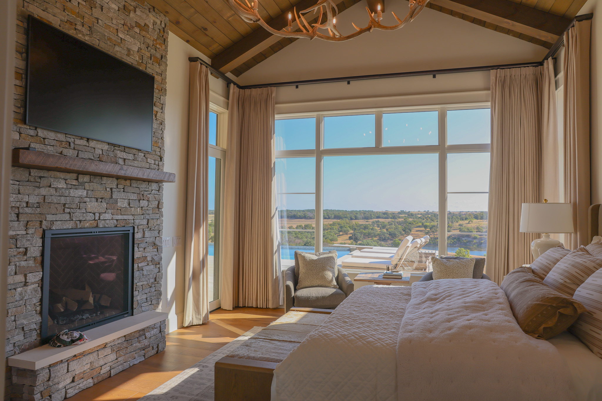 920 Ryan Road Bertram, TX 78605 - Photo 8 of 40 Floor-to-ceiling windows frame scenic views alongside a soaring timber ceiling and stone fireplace.