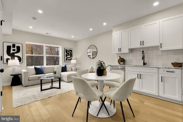 a kitchen with stainless steel appliances granite countertop a dining table chairs and white cabinets