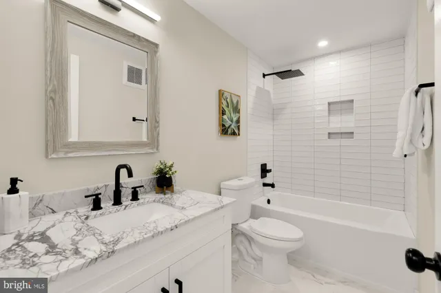 a bathroom with a granite countertop sink a toilet and shower
