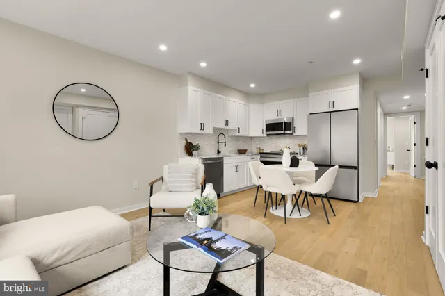 a living room with stainless steel appliances kitchen island a table and chairs